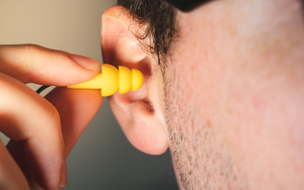 Man inserting combat earplugs into his ears.