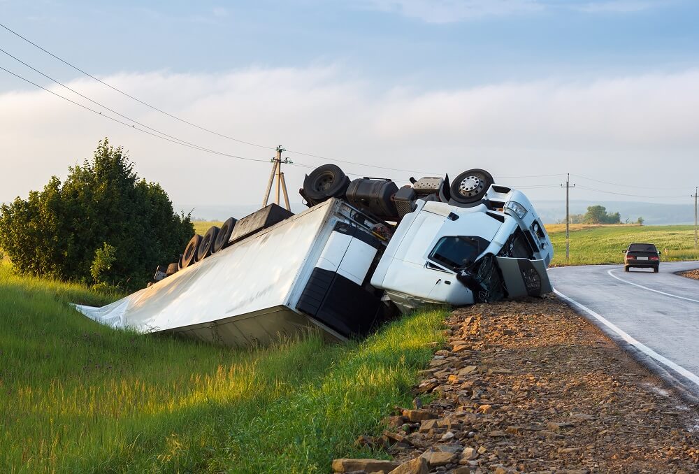 The truck lies in a ditch after the road accident.