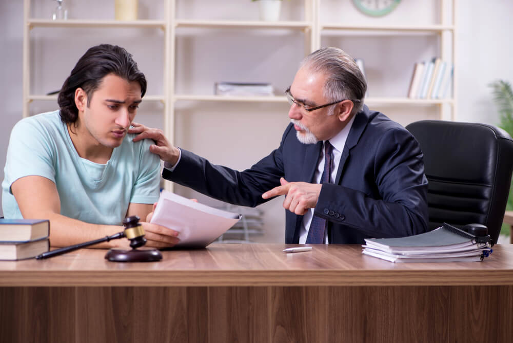 Sad client consulting lawyer for his personal injury case.