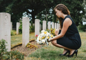 Young widow offering flowers to late husband.