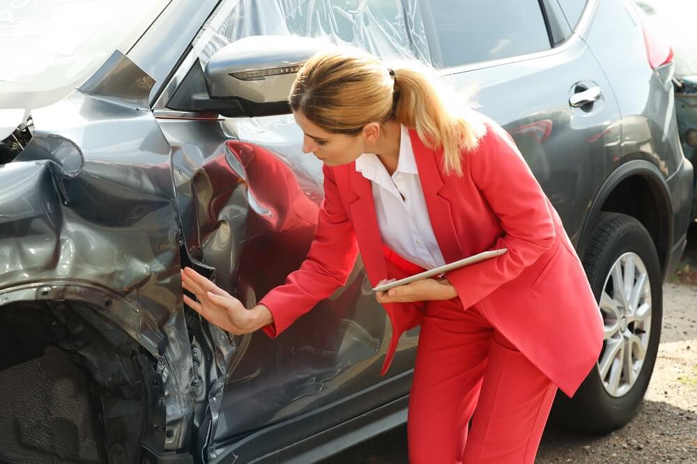 Lady insurance agent checking damages of car.