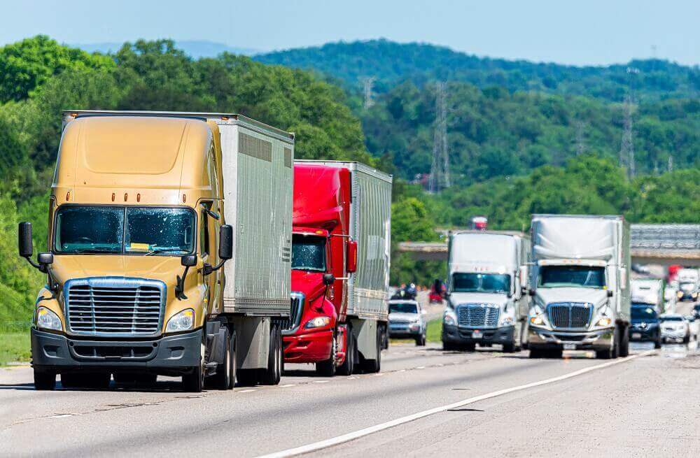 Commercial trucks in convoy passing interestate.