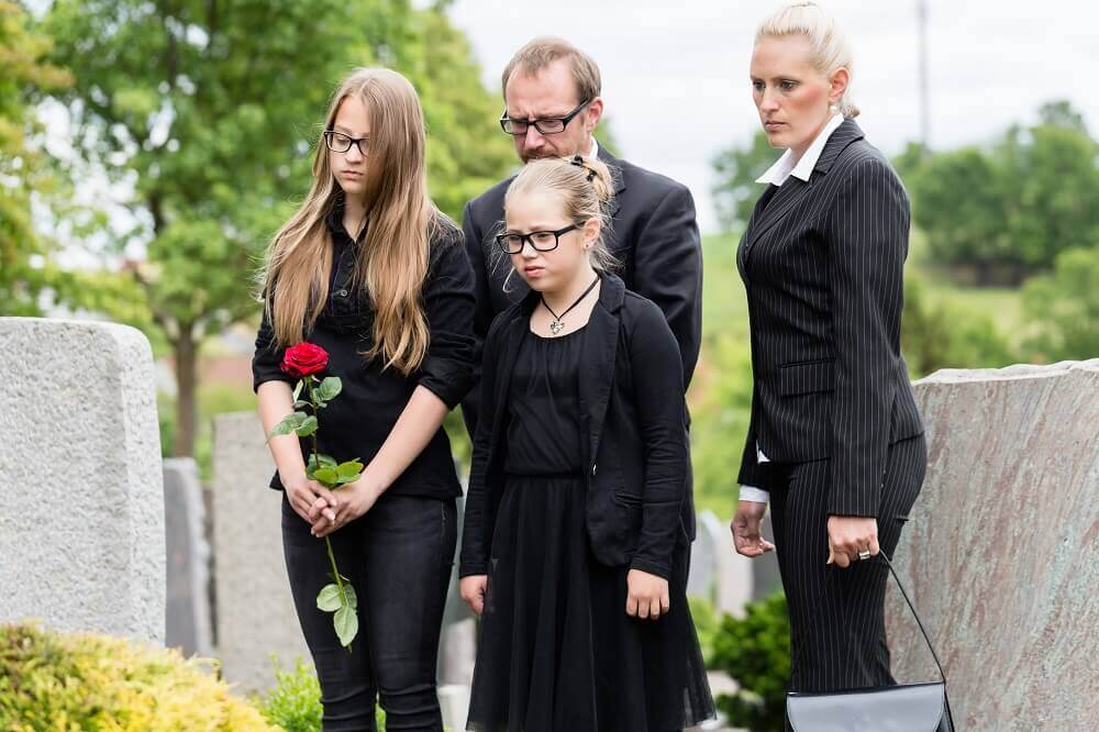 Sad family in the cemetery on the passing of their late mother.