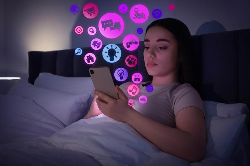 Internet addicted woman using mobile phone instead of sleeping at night.