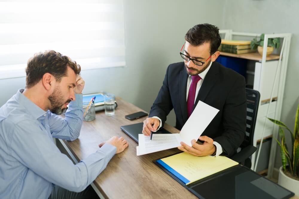 Male client receiving legal advice from a lawyer in a professional office setting, focusing on serious discussion.